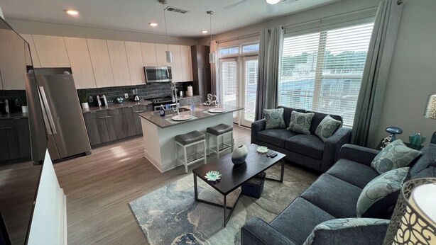A modern living room with a sofa, coffee table, and a dining area with a kitchen in the background. - Cozy 1-Bedroom Studio in Tranquil Atlanta (Atlanta)