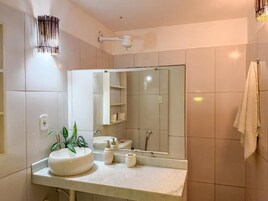 Um banheiro moderno com um espelho grande, azulejos brancos, um lavatório redondo e uma toalha pendurada na parede.