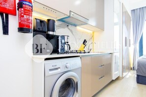 Una cucina moderna con lavatrice, macchina da caffè e estintore.
