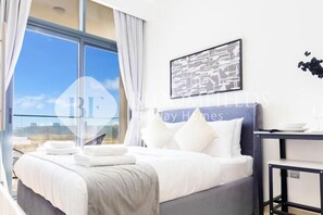 Una camera d'hotel con un letto, vista sulla spiaggia e un quadro appeso al muro.