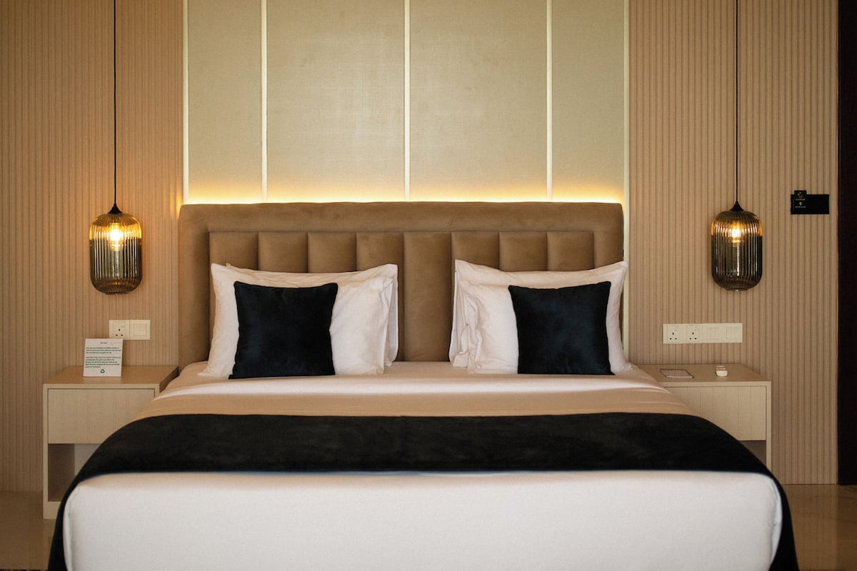 Ein modernes Hotelzimmer mit einem großen Bett, einem Deckenventilator und zwei Wandleuchten.