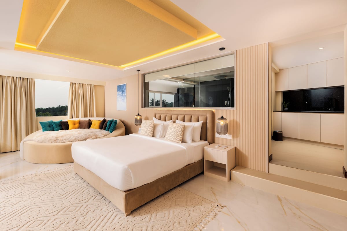 Ein modernes Schlafzimmer mit einem großen Bett, einer Sitzecke, einem Fernseher und Blick ins Freie.