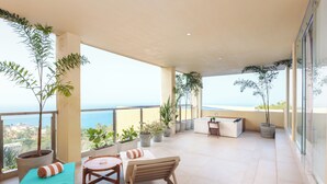 Ein Balkon mit Blumentöpfen, einem Tisch, Stühlen und Blick aufs Meer.