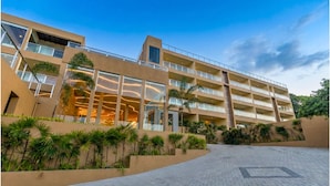 Ein mehrstöckiges Hotel mit modernem architektonischem Design, mit Balkonen, großen Fenstern und einem begrünten Innenhof.