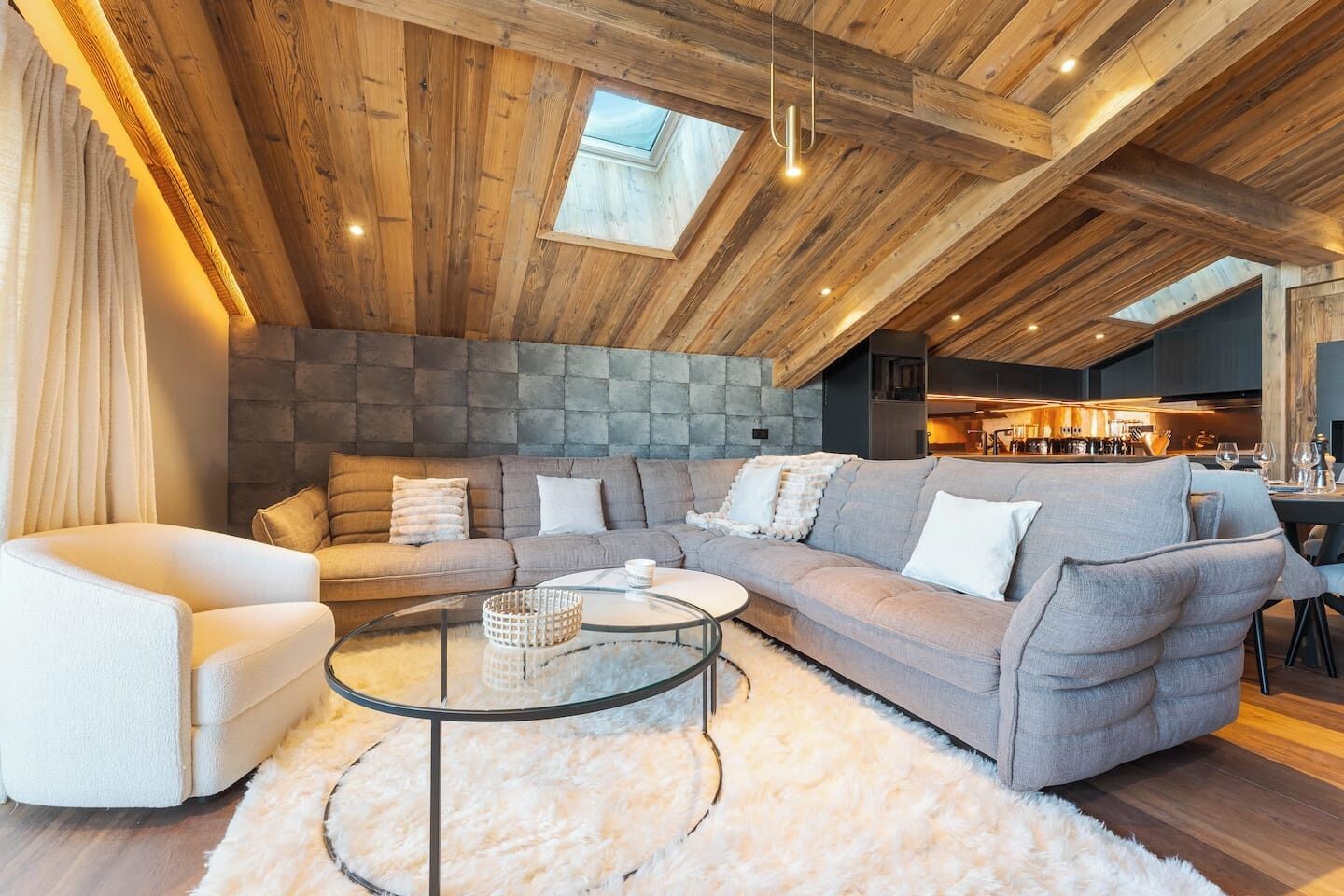 A modern living room with a sectional sofa, a glass coffee table, and a fluffy rug.