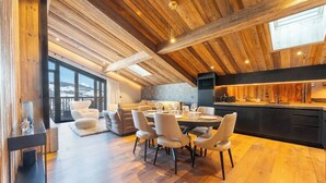 Une cuisine moderne dotée d’un îlot central, d’un coin repas avec une table ronde et des chaises, et d’une grande fenêtre offrant une vue sur l’extérieur.