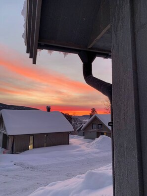 A snowy landscape with houses and a sunset.