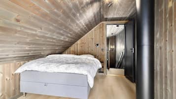 A bedroom with a sloped ceiling, a bed, a wardrobe, and a heater.