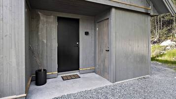 A modern building with a concrete exterior, a black door, and a small black planter with branches.