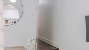 A hallway with a wooden floor, a white wall, and a round mirror. - The Hidden Courtyard | Erskineville (Erskineville)