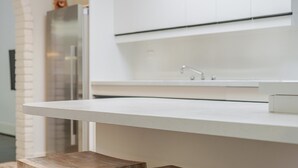 A modern kitchen with a white countertop, stainless steel appliances, and a built-in sink. - The Hidden Courtyard | Erskineville (Erskineville)