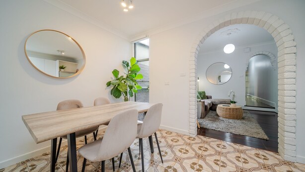 A modern dining area with a wooden table and chairs, a large mirror, and a potted plant. - The Hidden Courtyard | Erskineville (Erskineville)
