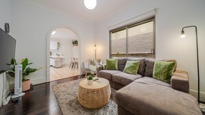 A living room with a sofa, a round coffee table, and a large window. - The Hidden Courtyard | Erskineville (Erskineville)
