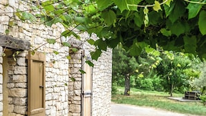 A stone building with a table and chairs outside, surrounded by greenery. - Provencal house with heated pool, jacuzzi and view 5 minutes from the Colorado (Viens)