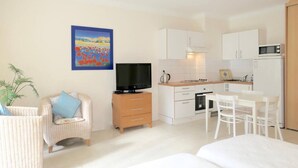 Ett kompakt bostadsutrymme med ett litet kök, en tv, en matplats och en soffa.