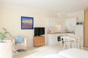 A compact living space with a kitchenette, a television, a dining area, and a sofa. - Charming Cannes Studio with Private Balcony – Near Rue d’Antibes & Beaches (Cannes)