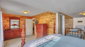 Une chambre avec des lambris en bois, un lit, une commode et une table de chevet.
