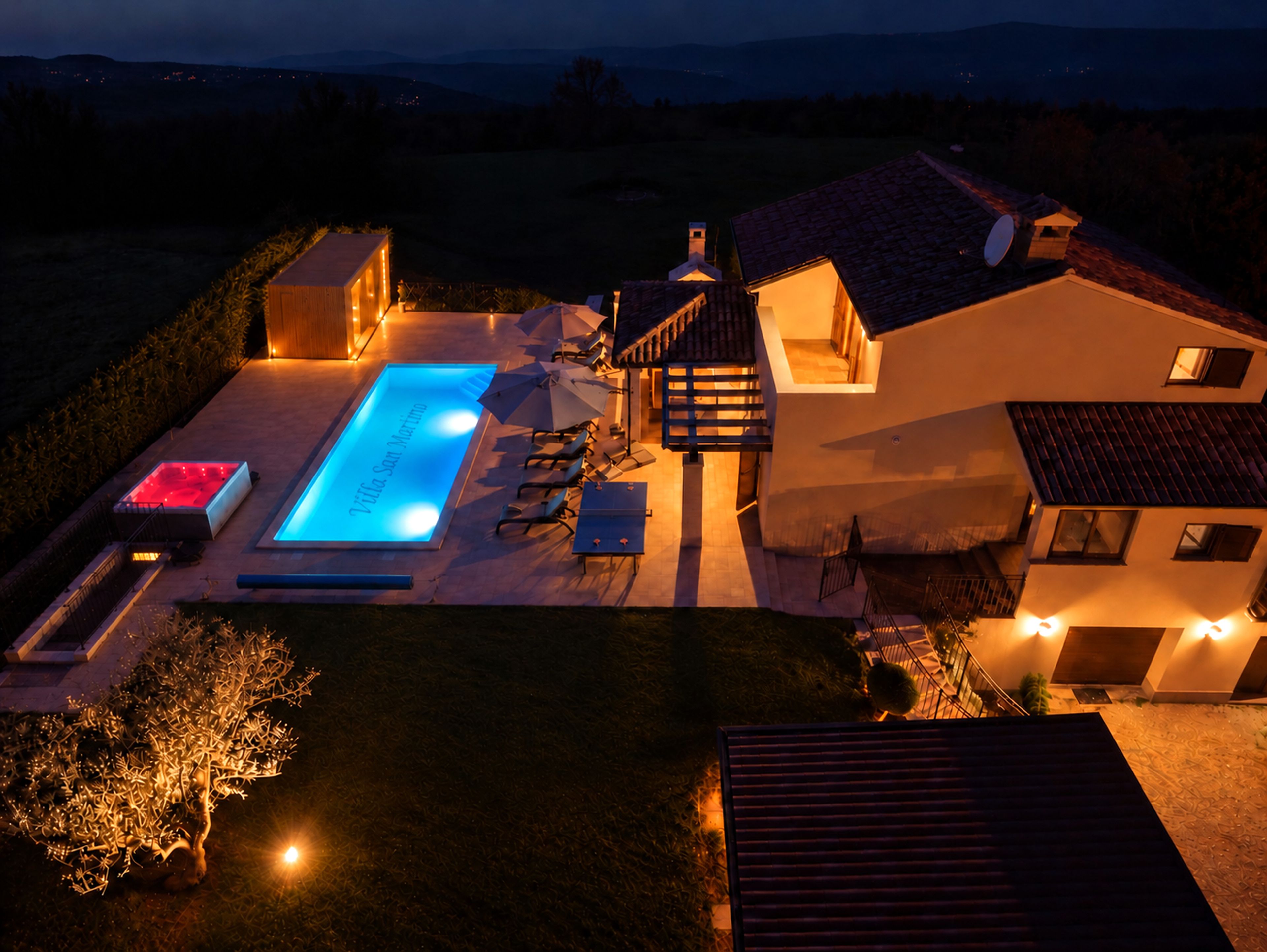 A villa with a swimming pool, outdoor seating, and a staircase leading to the upper floor.