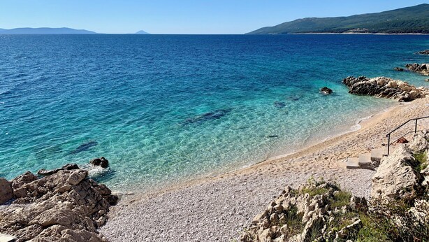 A clear coastal view with a rocky beach, calm sea, and distant mountains. - Modern Villa in Istria with Heated Pool, Jacuzzi & Total Privacy (Nedešćina)