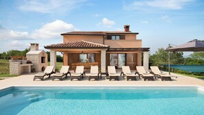 A two-story house with a swimming pool, lounge chairs, and a pergola. - Modern Villa in Istria with Heated Pool, Jacuzzi & Total Privacy (Nedešćina)