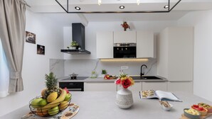 A modern kitchen with white cabinets, a stainless steel oven, and a central island with a fruit bowl and a vase of flowers. - Modern Villa in Istria with Heated Pool, Jacuzzi & Total Privacy (Nedešćina)