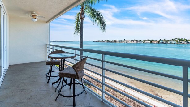 Uma varanda com vista para o mar, equipada com cadeiras de vime e uma pequena mesa.