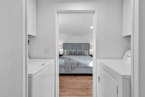 A narrow hallway leading to a bedroom with a bed, bedside tables, and a nightstand. - Seabreeze Serenity-2 Kings, 1 Queen, garage, large yard (Murrells Inlet)