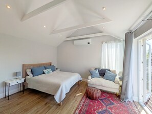 A bedroom with a bed, bedside table, and a sofa.