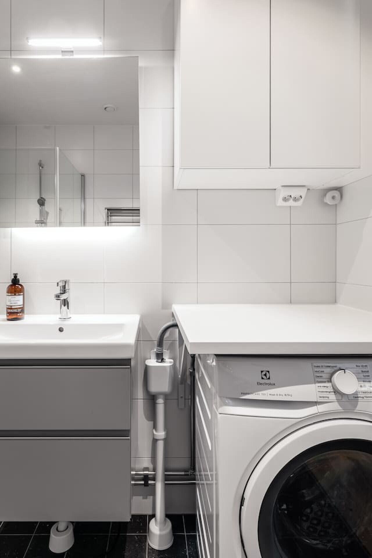 Une salle de bain moderne équipée d’un lavabo, d’un miroir et d’un lave-linge à chargement frontal.