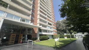Un edificio residenziale a più piani con balconi, un ingresso coperto e un prato curato.