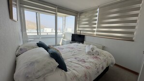 Una camera d'hotel con un letto, una televisione, una finestra con tende e vista sulla città.