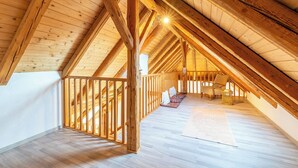 Une chambre mansardée avec des poutres apparentes, un plafond haut et une vue sur le ciel.