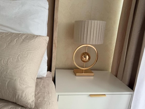 A neatly made bed with a patterned pillow, a bedside table with a lamp, and a drawer. - 77 on Independence Apartments (Windhoek)