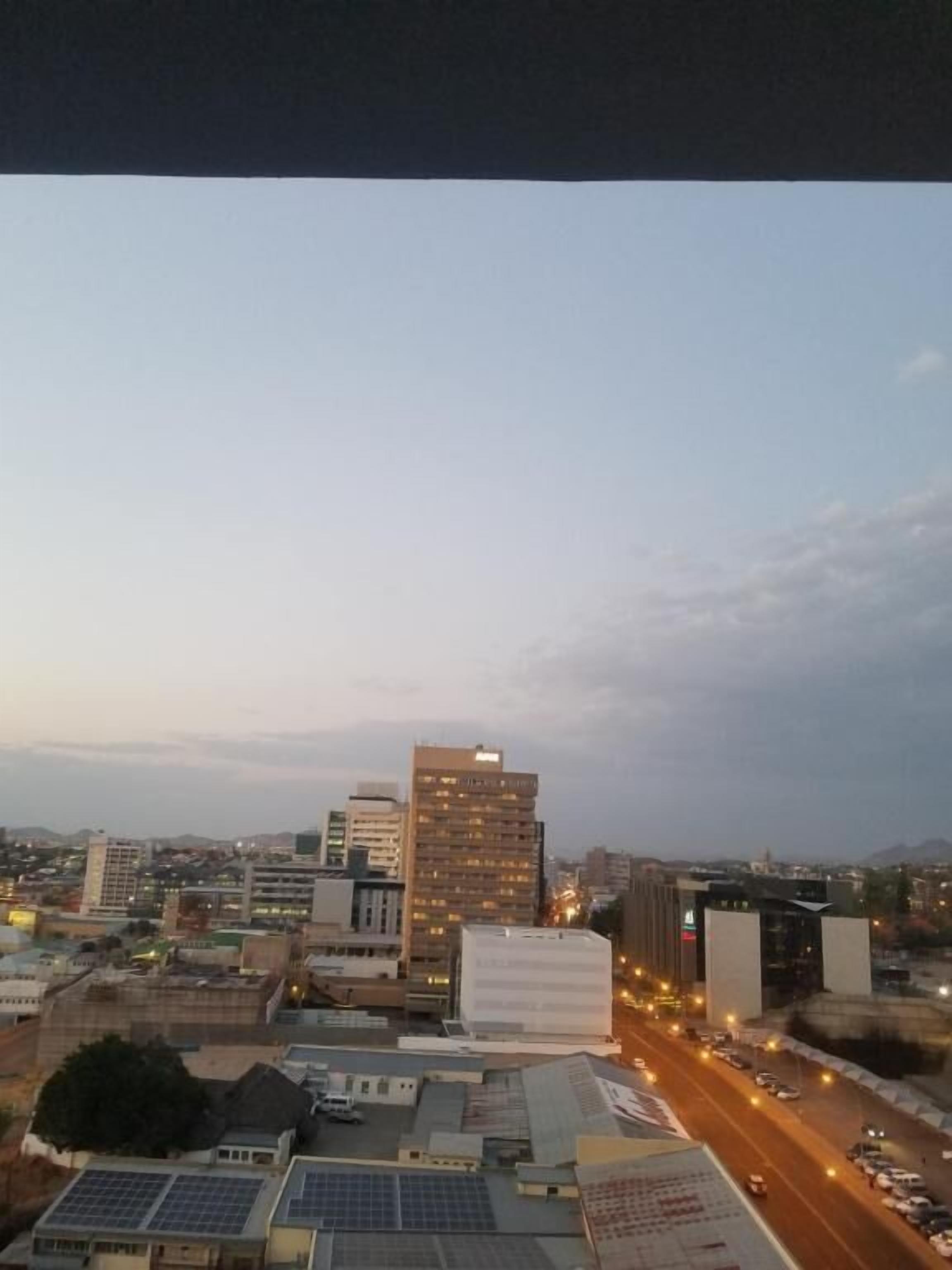A cityscape at dusk with buildings, roads, and a clear sky.