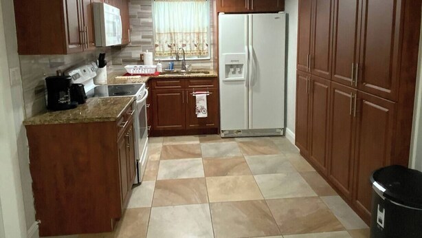 Una cocina con armarios de madera, un refrigerador blanco, una estufa y un lavamanos.