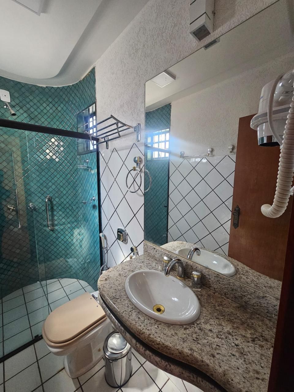 A bathroom with a glass-enclosed shower, a toilet, and two sinks with a granite countertop.