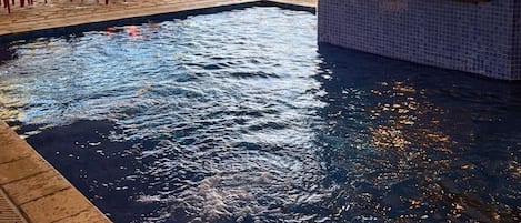 A pool area with a covered seating area, a bar with a view, and outdoor furniture.