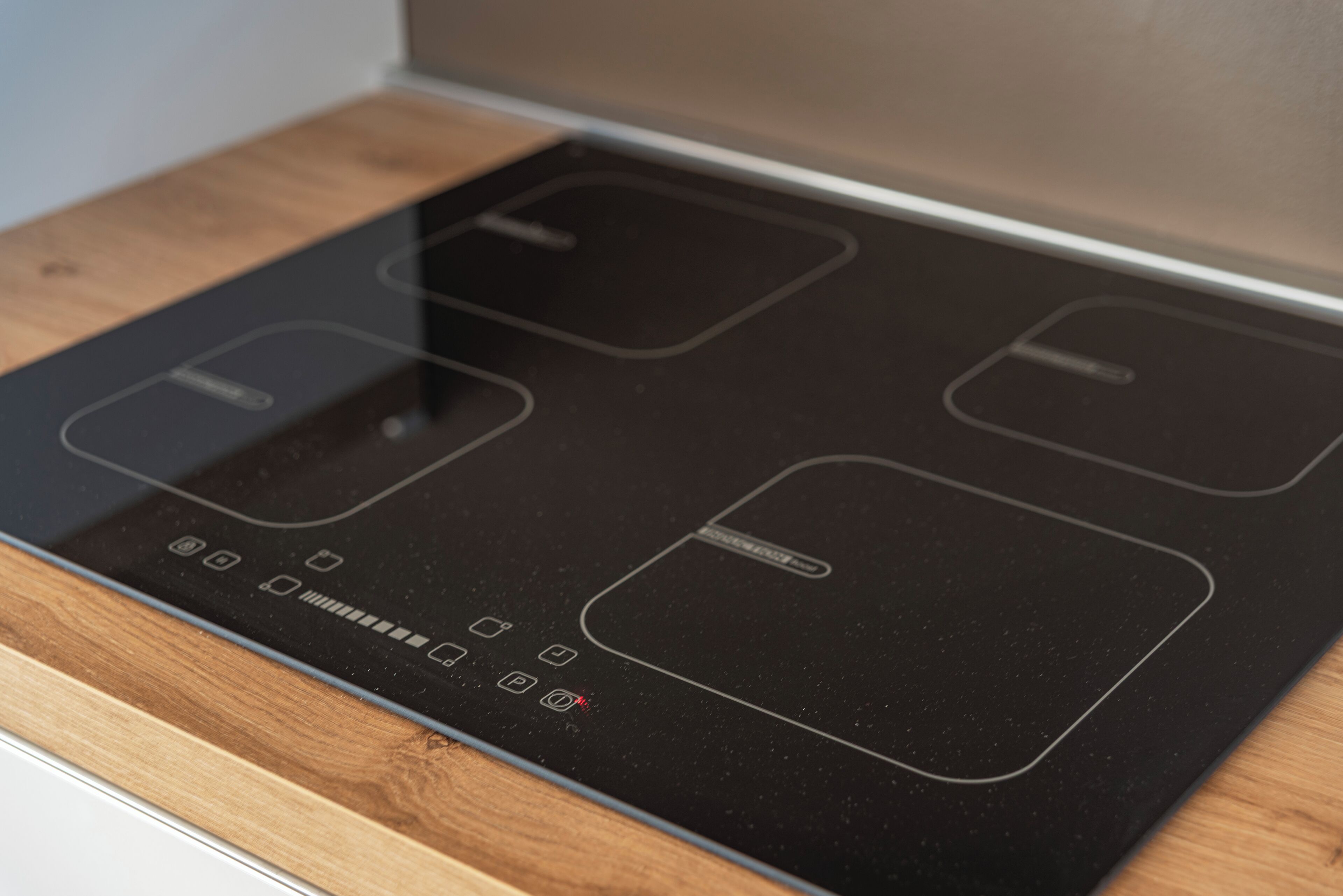 Een moderne keuken met een zwart inductiefornuis en een houten aanrecht.