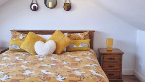 A bedroom with a wooden bed, yellow floral bedding, a bedside table with a lamp, and three wall-mounted mirrors. - Room-kings Room to Enjoy the Stars (Lusk)