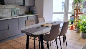 A modern kitchen with grey cabinets, a white countertop, and a dining area with a table and chairs. - Room-kings Room to Enjoy the Stars (Lusk)
