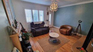 A living room with a sofa, a coffee table, a brown leather chair, a tripod, and a chandelier. - Room-kings Room to Enjoy the Stars (Lusk)