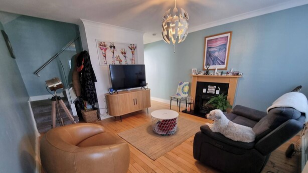 A living room with a sofa, a round coffee table, a television on a wooden cabinet, a fireplace, and a chandelier. - Room-kings Room to Enjoy the Stars (Lusk)