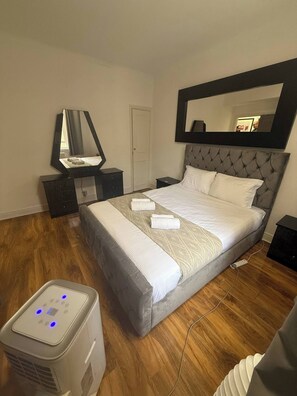 A neatly arranged bedroom with a bed, bedside tables, a mirror, and a heater. - Charming Central Apartment Steps From Hyde Park (London)