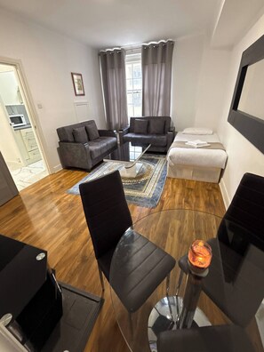 A modern living room with a sofa set, a coffee table, and a dining area with a table and chairs. - Charming Central Apartment Steps From Hyde Park (London)