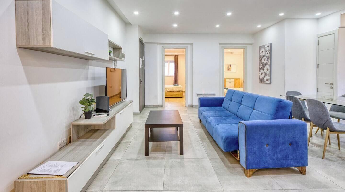 Una sala de estar moderna con un sofá, televisión y comedor.