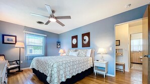 A bedroom with a bed, bedside lamps, a ceiling fan, and a window with blinds. - Sweet Slice of Old Florida Charm with modern amenities, large yard & beach gear (Holmes Beach)