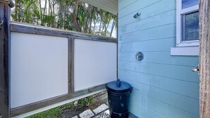 A small outdoor area with a trash can, a window, and a door. - Sweet Slice of Old Florida Charm with modern amenities, large yard & beach gear (Holmes Beach)