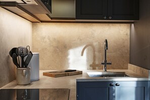 Eine moderne Küche mit Spüle aus Edelstahl, Schneidebrett aus Holz und einer Aufbewahrung für Küchenutensilien.