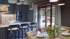 A modern kitchen with dark cabinetry, a central island, and pendant lighting. - Casa Pernice - Stylish Chianti Retreat with Pool & Vineyard Views (Gaiole in Chianti)