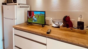 Eine kompakte Küche mit Mikrowelle, kleinem Kühlschrank, Fernseher und einer Holzarbeitsplatte.